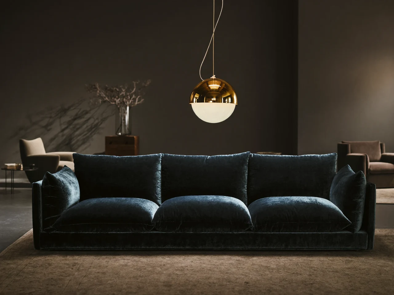Dunkel gehaltener Showroom mit Statement-Sofa und warmer Pendelleuchte als Konzeptillustration